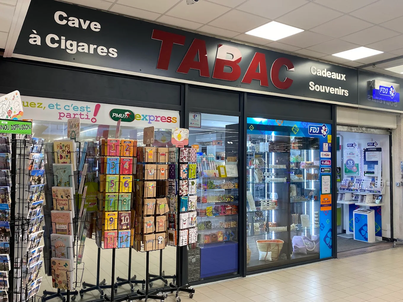 Devanture du tabac au centre commercial de La Fare-les-Oliviers : enseignes Cave à Cigares, Tabac, Cadeaux Souvenirs, PMU et FDJ